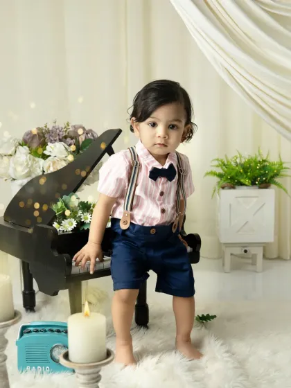 Standing tall by the piano. This shot captures a milestone moment of a baby learning to stand, set against a beautifully styled musical backdrop.
