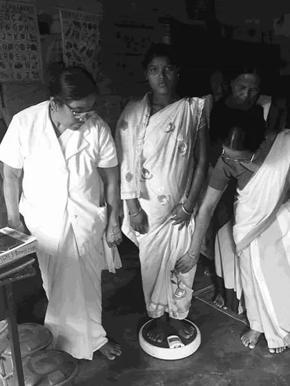 A woman being weighed at a health clinic, a crucial step in monitoring maternal health to prevent child malnutrition. The exhibition documented the entire cycle of care and its challenges.