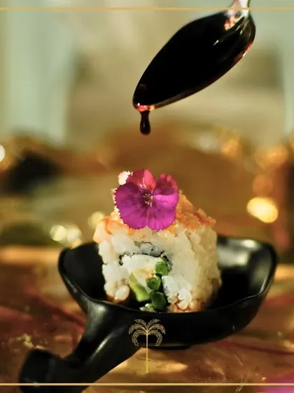 The final touch of sauce being drizzled onto a delicate sushi roll. This action shot captures the precision and artistry that goes into each and every appetizer we create.