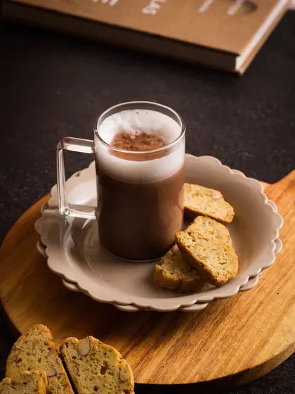 A moody shot of a Mocha Hot Chocolate. The dark, dramatic lighting and dusting of cocoa powder create a sense of indulgence and warmth.