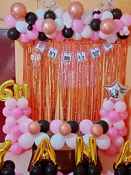 A full view of the 6-month birthday decoration. The setup includes balloon pillars, a balloon arch, and foil balloons indicating the milestone.