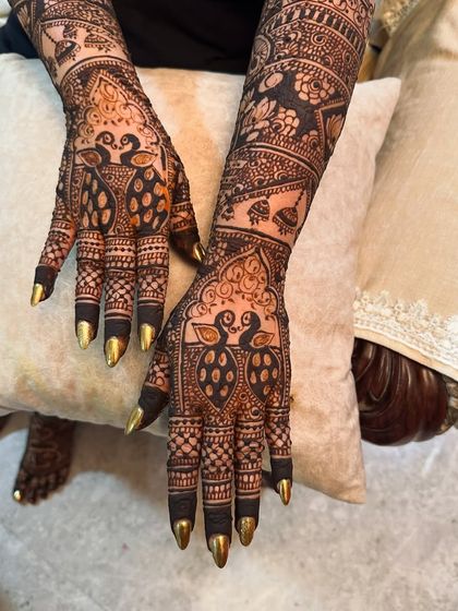 A close-up of peacock designs on the palms, with the fingertips dipped for a dark, traditional finish.
