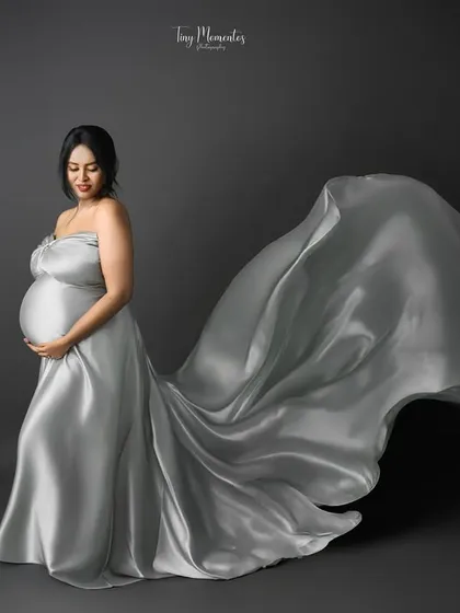 Capturing the gown in motion from the side, this portrait highlights the beautiful curve of the baby bump against the flowing fabric.