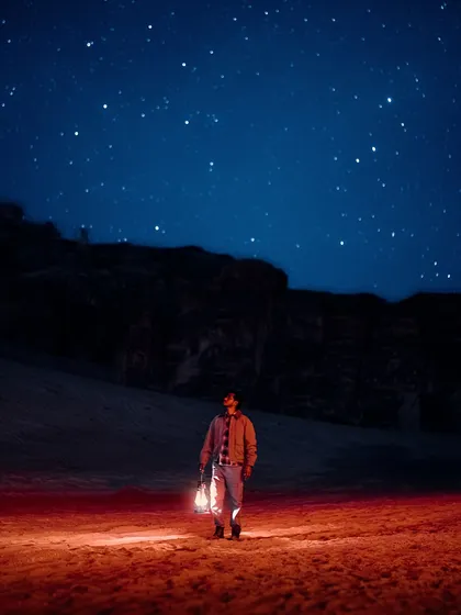 Stargazing in the Gharameel desert, Saudi Arabia. I used a lantern to light myself against a backdrop of millions of stars, capturing the magic of a night free from light pollution.