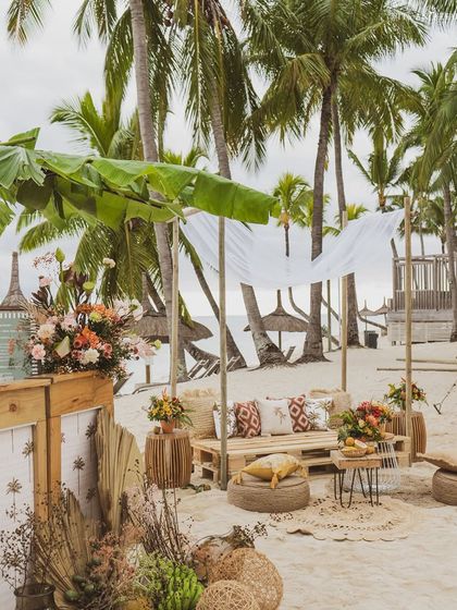 A lounge area on the beach in Mauritius, featuring rustic wooden pallet sofas and tropical print cushions.