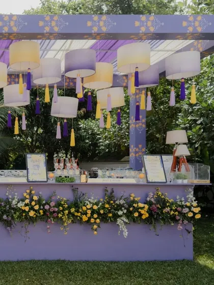 A full shot of the pastel Haldi cocktail bar, nestled in a lush green lawn. The design is both functional and beautiful, serving as a central hub for guests to mingle.