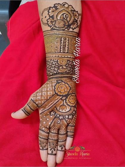 A beautiful siders henna design with floral patterns on the palm and a peacock mandala at the wrist.