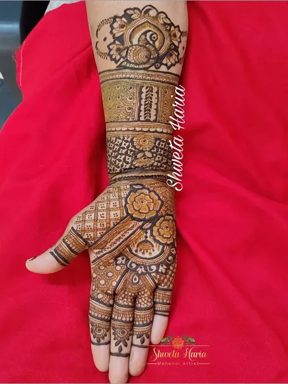 A detailed siders henna design covering one full arm. This piece combines floral bands, peacock motifs, and geometric patterns, making it a substantial and beautiful choice for a close relative.