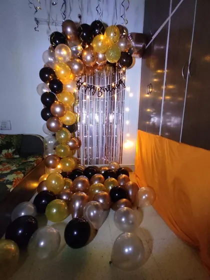 Here is a closer look at the birthday arch decor in a home setting. The combination of metallic and latex balloons in gold, black, and bronze creates a rich and celebratory feel, perfect for an evening party.