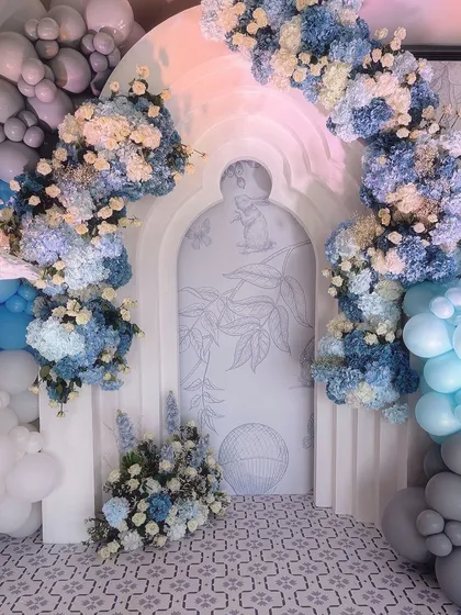 A beautiful floral and balloon archway in shades of blue, grey, and white. This elegant entrance sets the tone for the magical carnival celebration inside.