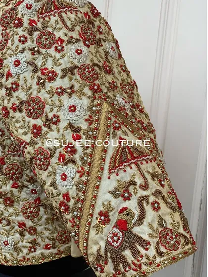A detailed look at the traditional craftsmanship I love. This close-up shows the hand-embroidered elephant and umbrella motifs, part of a wedding procession theme, brought to life with zardozi and thread work on a bridal blouse sleeve.