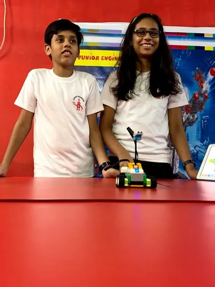 Two students collaborate on a robotics project, working together to program their LEGO vehicle using a tablet. Our classes emphasize teamwork and peer learning to solve engineering challenges.