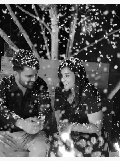 A black and white shot from a pre-wedding session with a bonfire and artificial snow. This creates a magical, cozy atmosphere that is perfect for romantic and dreamy couple photos.