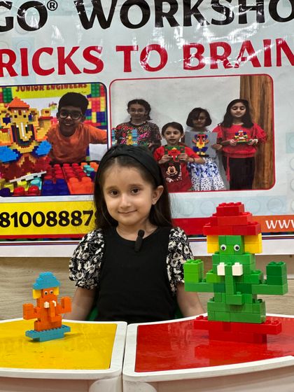 A young girl proudly shows off two different LEGO models she made during the Ganpati workshop.