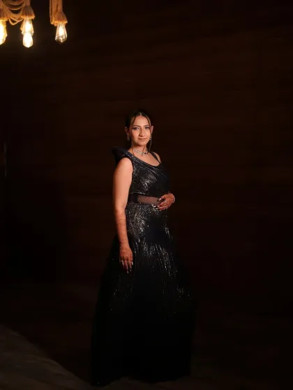 A full-length shot under dramatic lighting. This image showcases the entire silhouette of her Sangeet outfit and the confidence she exudes.