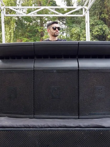Standing behind a powerful sound system at an outdoor event. Delivering crisp, clear sound is crucial for any party, especially for a baraat or outdoor celebration where the music needs to carry.