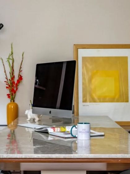 A detail shot of an executive desk, showing how we curate art and decor to personalize a workspace. The clean lines of the desk and shelving are softened by colorful art and personal items.