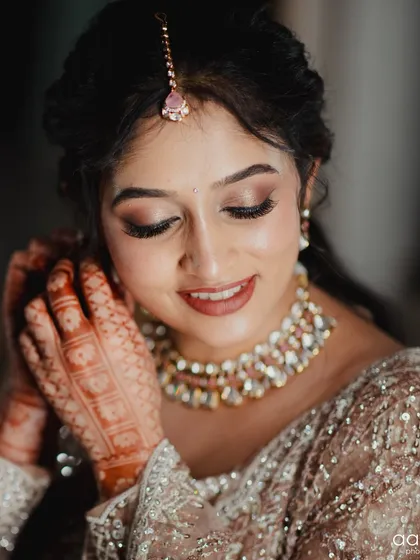 Those quiet moments before the ceremony are so special. This bride is getting ready, putting on a beautiful Kundan choker that perfectly matches her elegant, sequined lehenga.