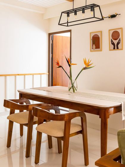 Simple and warm, this dining area features a classic wooden table and chairs. The industrial-style pendant light and minimalist art on the wall add a touch of modern character.