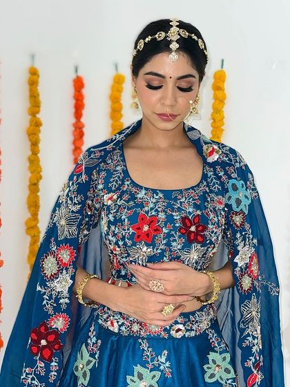 A serene portrait showing the delicate eye makeup that complements her beautiful blue floral lehenga.