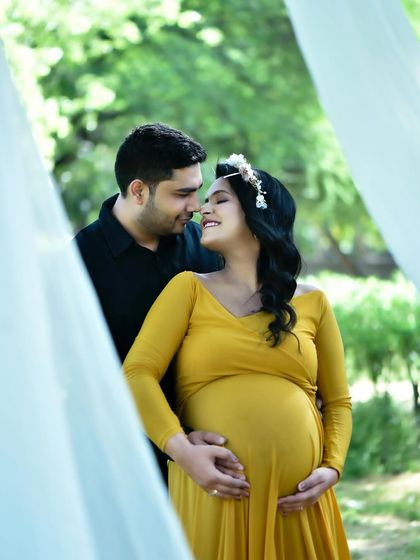 An intimate couple's portrait taken during an outdoor maternity shoot. This candid moment captures the connection between the parents-to-be, framed by natural light and greenery.