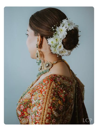 A close-up shot of the bride's elegant floral hair bun and intricate jewelry from the back.