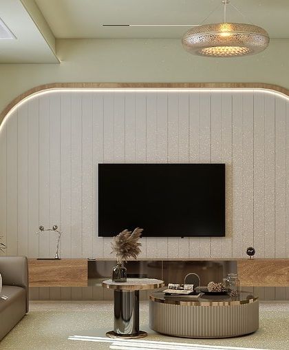 This living room design uses a soft, neutral color palette with pops of green to create a calming effect. The arched feature wall with integrated lighting elegantly frames the entertainment unit, making it a central design element.