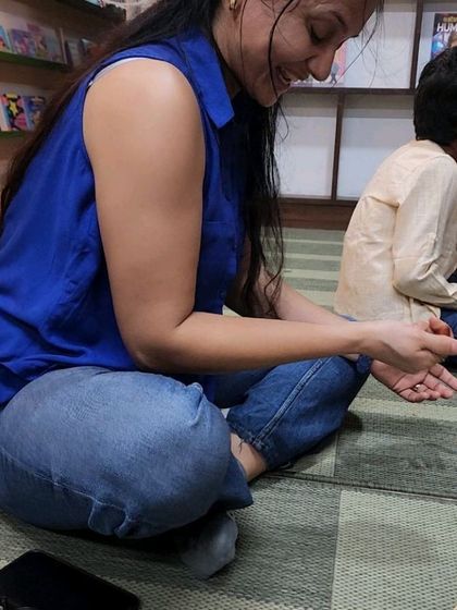 A parent fully engaged in learning a traditional Indian game alongside the children. Our workshops are designed to be fun for all ages, encouraging families to learn and play together.