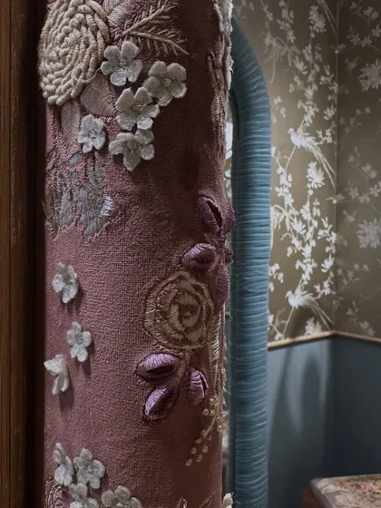 A close-up of the hand-embroidered fabric used to wrap the arches. This level of 3D appliqué and detailed threadwork turns a simple architectural element into a piece of textile art, meant to be appreciated up close as you walk through.