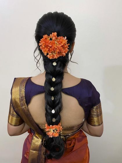 A simple and beautiful braid for a special occasion, decorated with pearl-centered flowers and two bunches of vibrant orange flowers for a pop of color.