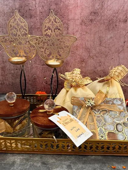 I love creating hampers that feel personal and luxurious. This one, set on a golden tray, combines crystal-lid jars, elegant potlis, and two stunning leaf-design T-light holders, making it a complete festive gift.