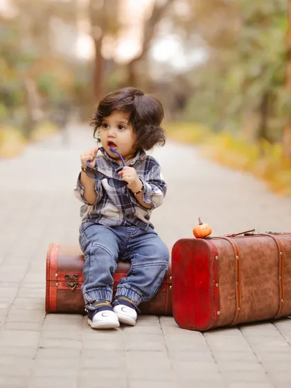 A 'little traveler' themed shoot, with a baby boy sitting on vintage suitcases and playfully chewing on his sunglasses.