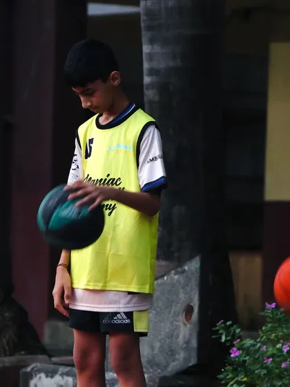 A young player in a yellow bib concentrates on his ball-handling. We teach our players to be comfortable and confident with the ball in their hands.