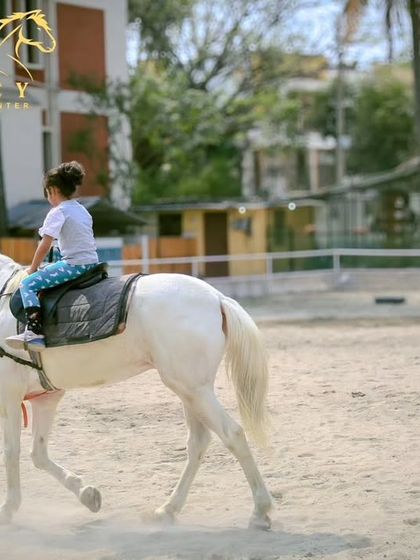 A young girl enjoys her lesson on a calm white horse. Our instructor is always close by to guide and ensure safety, making it a perfect start for kids.