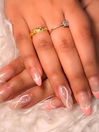 A fun and modern French manicure using a soft pink tip and abstract silver glitter swirls.