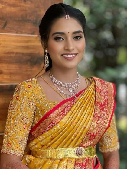 A smiling bride in her yellow and red Kanchivaram ensemble. The custom blouse is fully embroidered, making it as much of a statement piece as the saree itself.