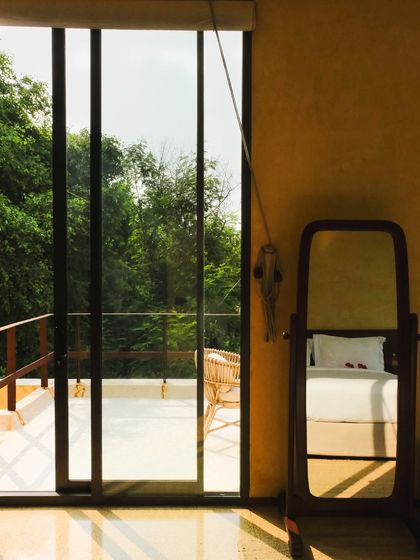 A mirror in a suite reflects the neatly made bed, creating a sense of layered space and tranquility.