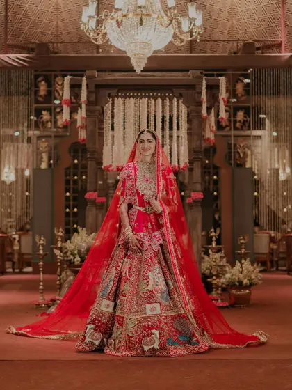 A full-length portrait of the bride, showcasing her magnificent lehenga with its long train against the backdrop of the grand mandap. I ensure the venue layout allows for such breathtaking shots.