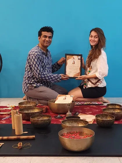 Presenting a certificate to a student after she successfully completed the Sound Healing course. The setup includes various Tibetan bowls used during the training.