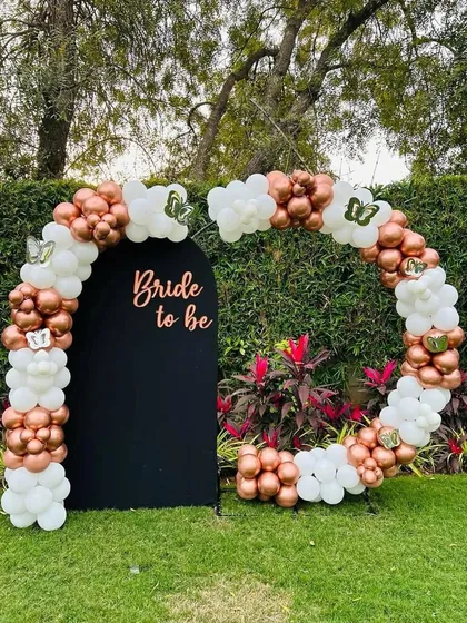 We created this elegant "Bride to be" backdrop for a garden party. A circular balloon arch in rose gold and white wraps around a custom black panel, creating a sophisticated and modern photo opportunity for the bride and her guests.