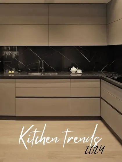 A trendy kitchen design for 2024, featuring beige cabinets paired with a dramatic black marble backsplash and countertop. The handleless design maintains a clean and uncluttered look.