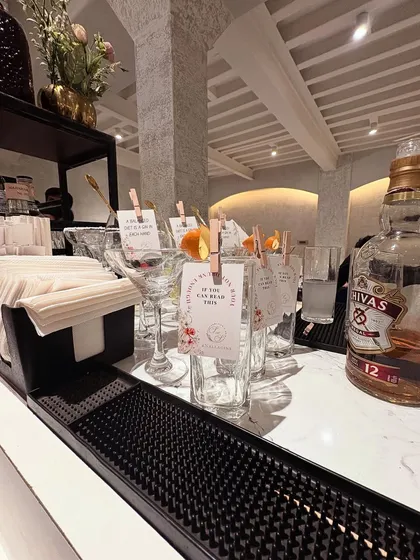 A clean and modern bar setup with a white marble top. The focus here is on simplicity and elegance, with personalized drink tags clipped to the glasses adding a thoughtful, custom touch for the guests.