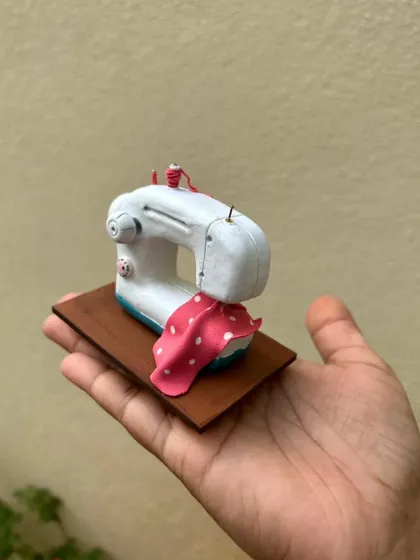 Holding the custom sewing machine miniature. It's small enough to fit in your palm but carries a big, personal message.