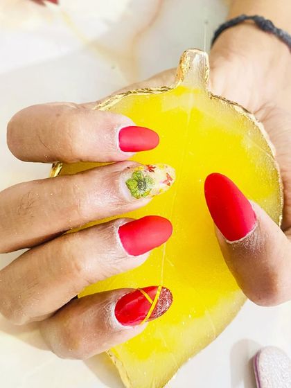 This student's work features a matte red finish with an accent nail showcasing an encapsulated dry flower. This technique is a beautiful way to incorporate natural elements into nail art.