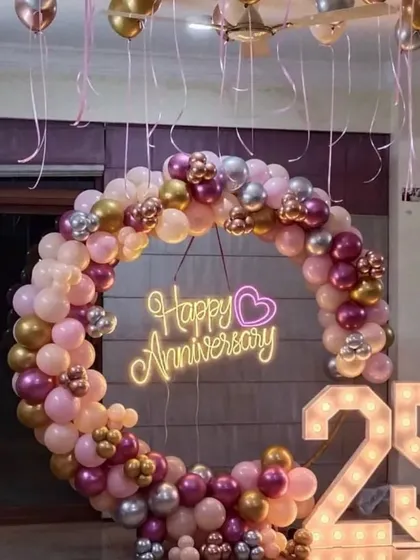 For this 25th anniversary party at home, we created a beautiful focal point with a full balloon ring in shades of pink, rose gold, and silver. The "Happy Anniversary" neon sign and large light-up marquee numbers for the milestone year made the space feel special and festive.