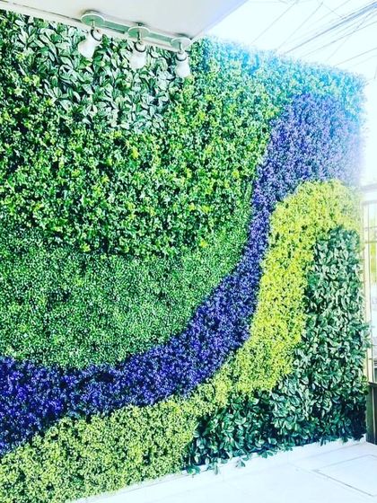 A custom green wall with a flowing, multi-colored design. I used different shades of green, blue, and light green foliage to create a unique, artistic pattern for this outdoor space.