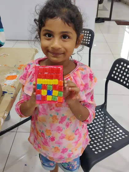 This happy girl is showing off the colorful mosaic box she made during a group art party and magic show.