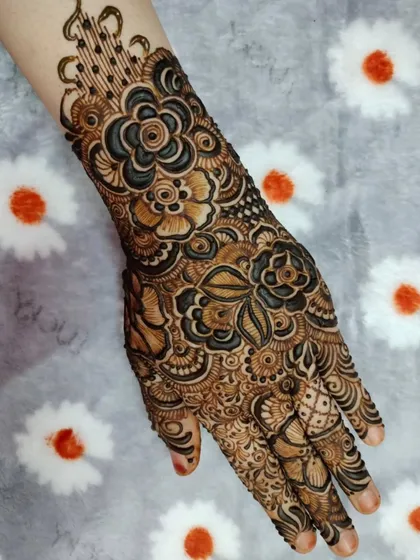A close-up of a full-hand design, showcasing the mix of bold, dark flowers and delicate, finely-shaded ones.