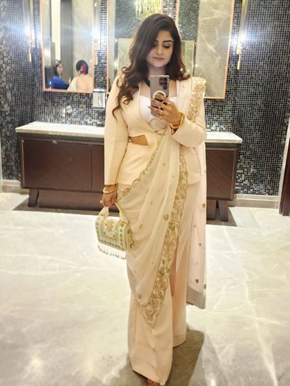 A mirror selfie capturing the details of the powder peach powersuit. The side cutouts and zardozi dupatta blend modern power dressing with traditional Indian elegance.