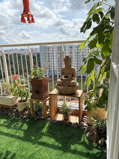 Another angle of the serene Buddha-themed balcony, showing how we used a mix of flowering plants and greenery to create a layered look. The space is designed to handle the harsh west sun while staying beautiful.